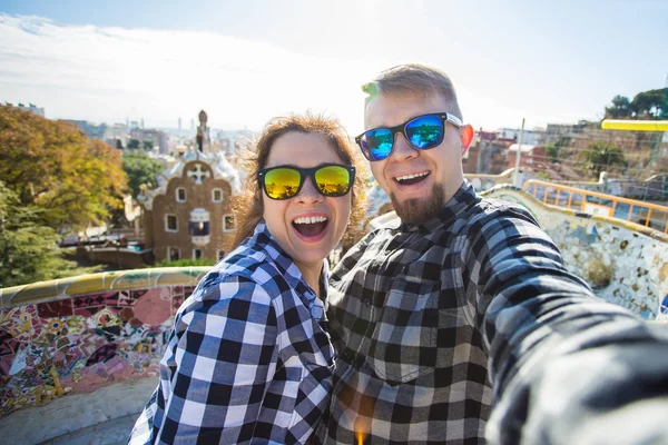 Funny young couple looking at camera taking photo with smart phone smiling in Park Guell, Barcelona, Spain. — Stock Photo, Image