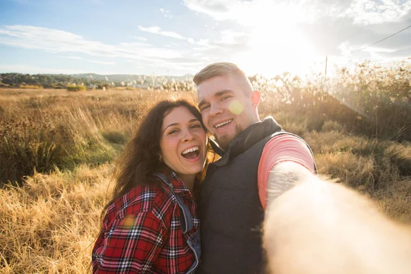 Resor, semester och naturen koncept - lyckliga paret tar en selfie på ett fält — Stockfoto