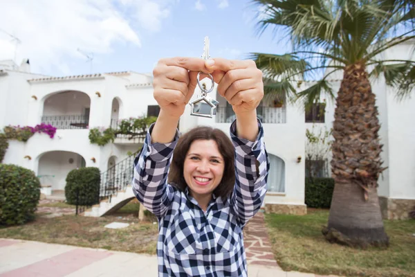Concepto inmobiliario y inmobiliario. Feliz propiedad. Atractiva joven mujer sosteniendo llaves mientras está de pie al aire libre contra la nueva casa . —  Fotos de Stock