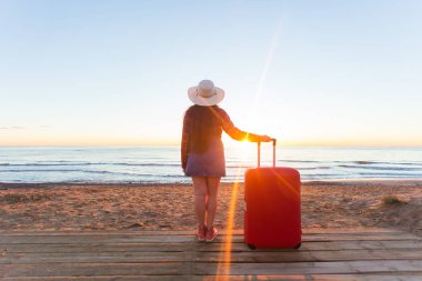 Tatil, seyahat ve Turizm kavramı - kumlu plaj arka plan üzerinde kırmızı çanta güzel kadınlar