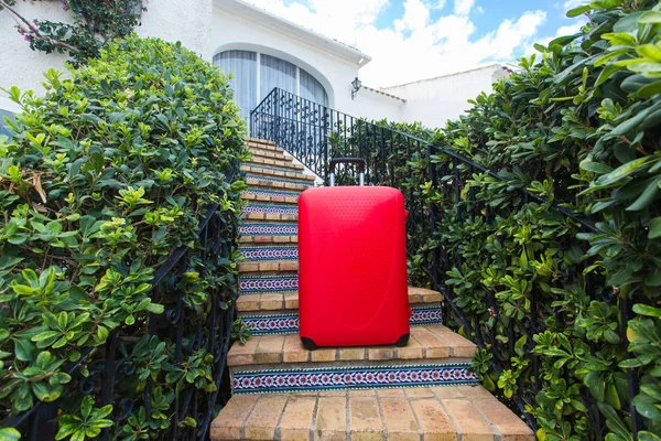 Ταξίδι, τουρισμός και αξεσουάρ έννοια - κόκκινη βαλίτσα στέκεται πάνω σε σκάλες και είναι έτοιμο να ταξιδέψει — Φωτογραφία Αρχείου