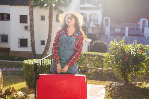 Reisen, Tourismus und Menschen - eine fröhliche junge Frau mit Hut trägt einen riesigen roten Koffer und lächelt über den Hintergrund der Natur — Stockfoto