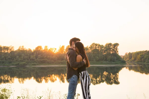 Романтическая и народная концепция - молодая пара, обнимающая друг друга у реки или озера и наслаждающаяся летним временем — стоковое фото