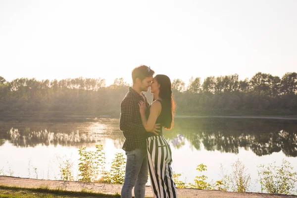 Romântica, natureza e conceito de pessoas - jovem casal beijando na praia do lago e abraçando — Fotografia de Stock