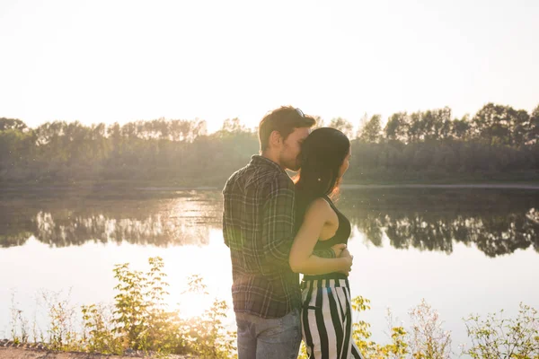 Människor, kärlek och natur koncept - ung vacker kvinna och stilig man omfamnar varandra över vatten bakgrund — Stockfoto