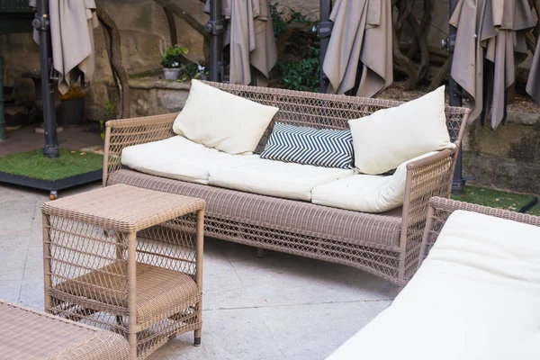 Outdoors lounge zone with brown wicker sofa and small coffee table