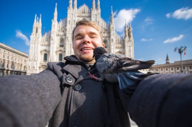 Kış seyahat, tatil ve kuşlar kavramı - selfie güvercinler yakınındaki Milan Katedrali Duomo di Milano, İtalya ile alarak genç komik adam.