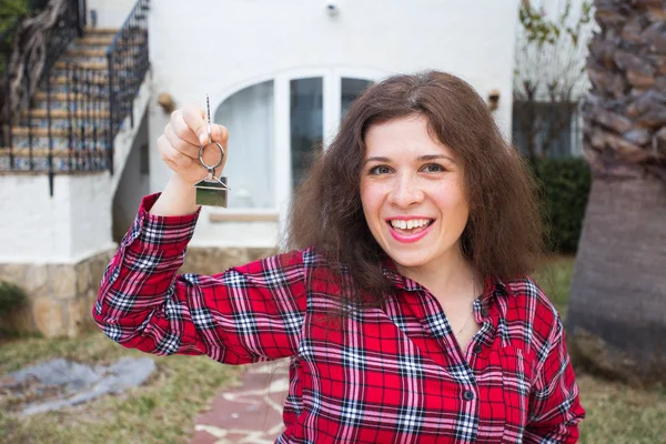 Nieuwe woning, huis, eigendom en huurder - grappige jongedame toets ingedrukt te houden tegenover haar nieuwe huis na het kopen van onroerend goed — Stockfoto