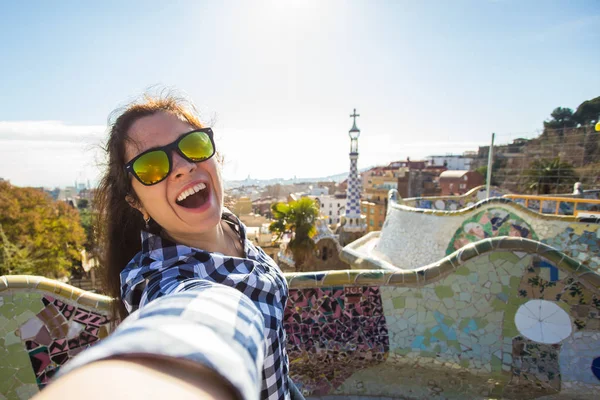 Travel and holidays concept - Young happy woman making selfie portrait with smartphone in Park Guell, Barcelona, Spain. — Stock Photo, Image