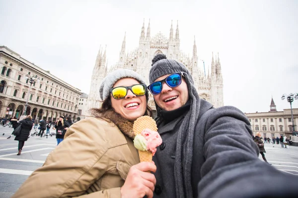 Travel in winter and Italy concept - Happy young couple take selfie photo with ice-cream in front of Milan Duomo Cathedral. — Stock Photo, Image
