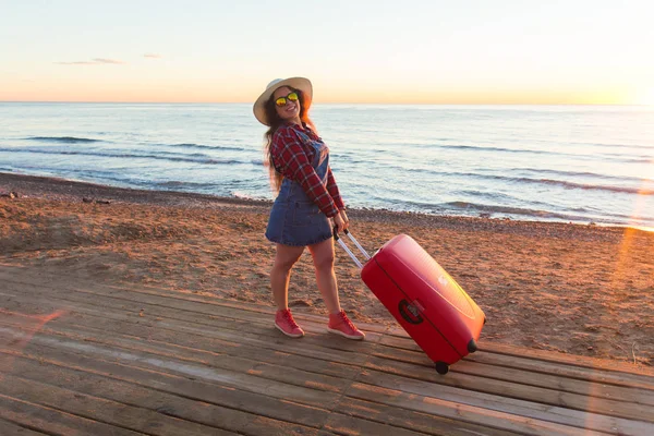 El verano, el viaje y el concepto de vacaciones - la joven feliz con la maleta en la orilla del mar — Foto de Stock