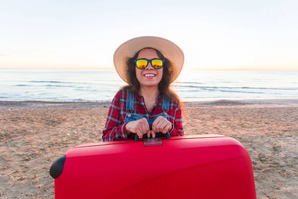 Reise-, Urlaubs- und Personenkonzept - glücklich lachende Touristin mit rotem Koffer am Meer — Stockfoto