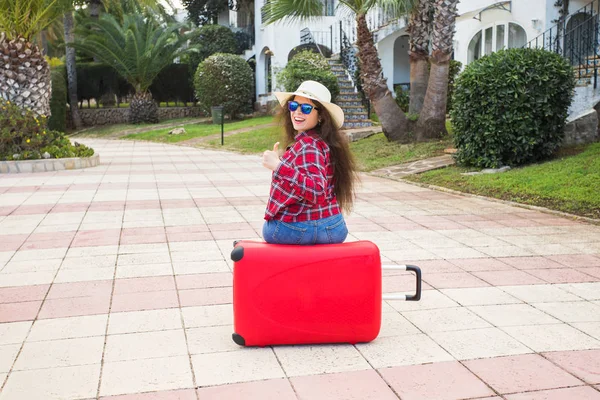 Viajes, turismo y concepto de personas - niña feliz sentada en la maleta roja en gafas — Foto de Stock