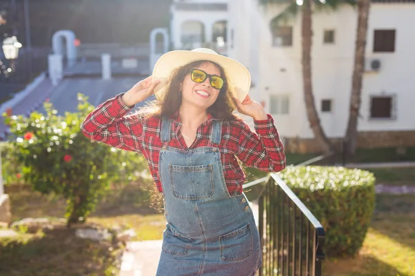 Reizen, zomer en vakantie concept - gelukkige jonge vrouw in hoed lachend over de achtergrond van het hotel — Stockfoto