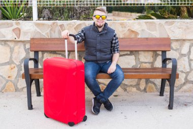 Seyahat, insanlar ve tatil kavramı - bavulla oturan genç adam. Gezi hazır