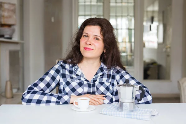 Food, drink and people concept - Beautiful young woman in coffee house drinks coffee