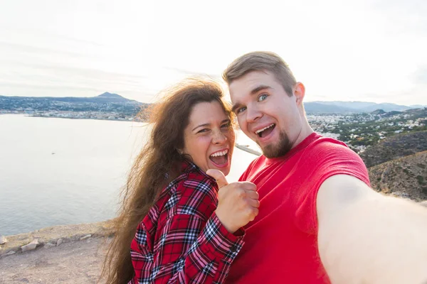 Koncepcja podróży, wakacji i wczasów - para piękny posiadające zabawy, biorąc selfie, szalony twarze emocjonalne i śmiejąc się. — Zdjęcie stockowe