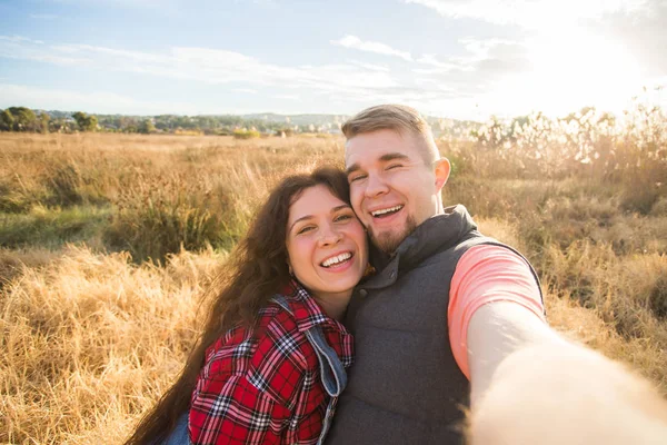 Reise-, Urlaubs- und Urlaubskonzept - glückliches Paar macht Selfie vor Hintergrund auf dem Feld — Stockfoto