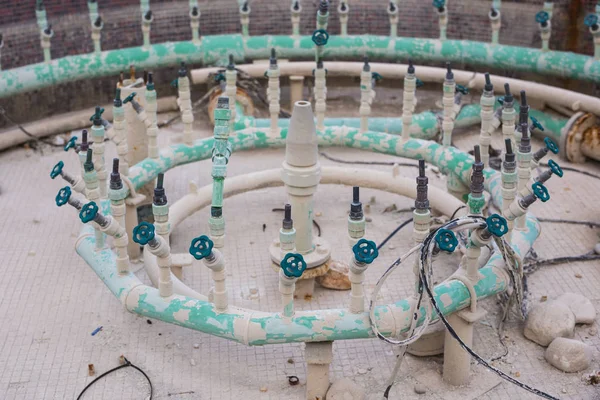 Engineering system of pipes and illumination jets of a fountain drained for maintenance or servicing on a summer day — Stock Photo, Image