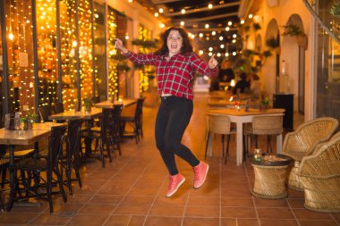 Gece hayatı, insanlar ve eğlence kavramı - güzel genç kadın sokakta parlak restoran yakınında gece poz veriyor