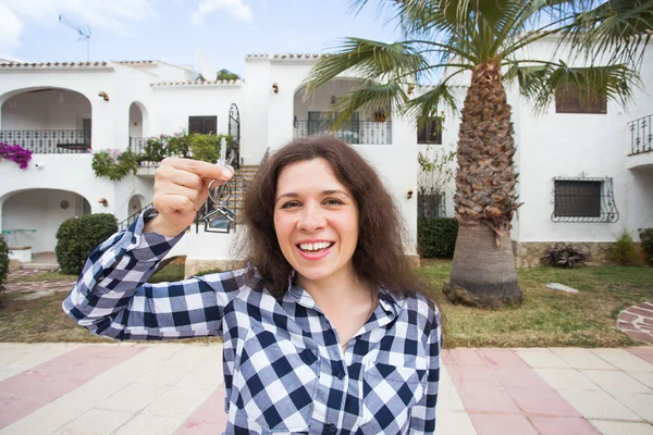 Eigendom, onroerend goed, kopen en huren van de concept - vrouw met sleutels permanent buiten nieuwe huis — Stockfoto