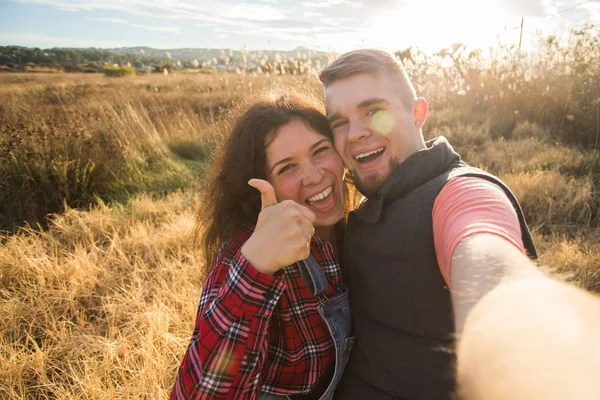 Resor, semester och naturen koncept - lyckliga paret tar en selfie på ett fält — Stockfoto