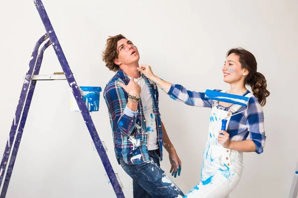 Reparación, renovación y amor concepto de pareja - familia joven haciendo redecoración y pintando paredes juntos y riendo . — Foto de Stock