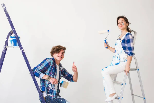 Teamwork and repair concept - young couple doing a renovation in new apartment and showing thumbs up — Stock Photo, Image