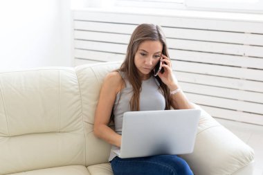 Teknolojileri, eğlence ve insanlar kavramı - o beyaz kanepe oturma ve netbook ve mobil sohbet genç kadın