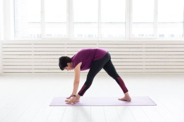 Yoga, meditasyon, millet kavramı - bir yoga yaparken orta yaşlı bir kadın ve bir asana yapmaya çalışın