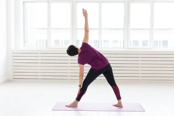 Yoga, armonía, concepto de personas - una mujer de mediana edad está practicando el yoga y mirando por la ventana —  Fotos de Stock