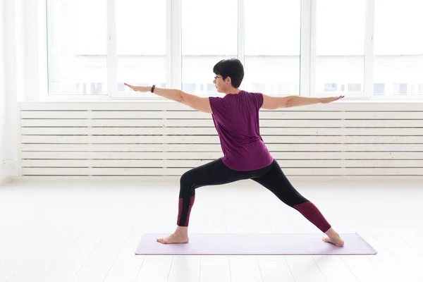 Gente, deporte y concepto de salud - Mujer de mediana edad practicando yoga, de pie en Guerrero dos ejercicios —  Fotos de Stock