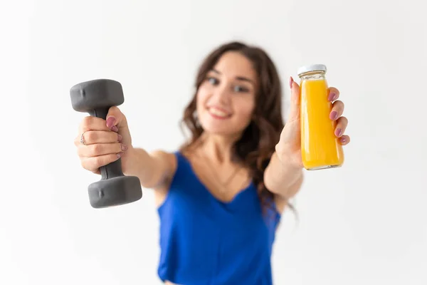 Sport, stile di vita sano, concetto di persone - giovane donna con un manubrio in mano e una bottiglia di succo in un'altra mano — Foto Stock