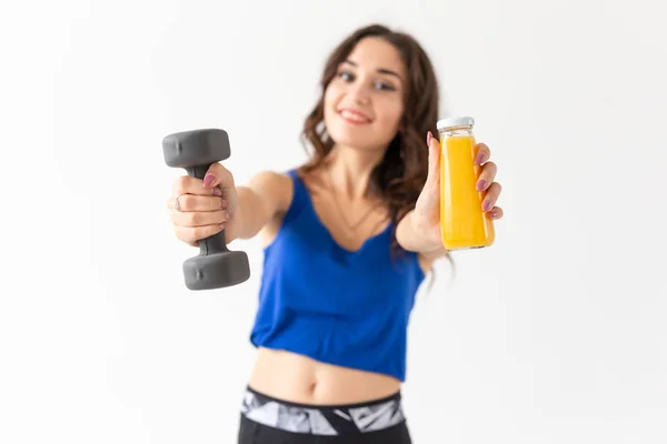 Esporte, estilo de vida saudável, conceito de pessoas - jovem mulher com um halteres na mão e uma garrafa de suco em outra mão — Fotografia de Stock
