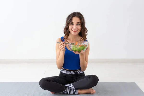 Estilo de vida saludable, personas y concepto deportivo - Mujer de yoga con un tazón de ensalada de verduras — Foto de Stock