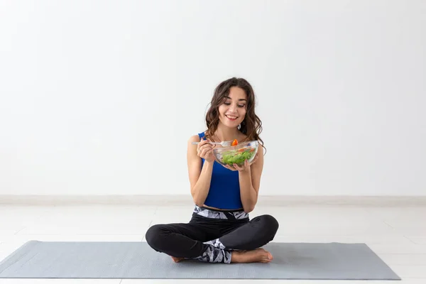 Estilo de vida saludable, personas y concepto deportivo - Mujer de yoga con un tazón de ensalada de verduras — Foto de Stock