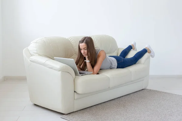 Tecnologías, freelance y el concepto de la gente - mujer bastante joven acostada en el sofá con el ordenador portátil — Foto de Stock
