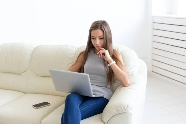 Koncepcja freelance i ludzie - młoda kobieta siedzi na kanapie i pracę na laptopie — Zdjęcie stockowe