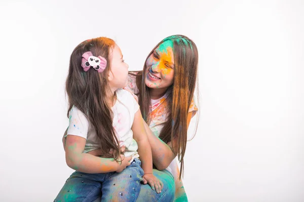Conceito de família, amor e diversão - jovem mulher com filhinha sorrindo junto, sujo em cores no festival de holi — Fotografia de Stock