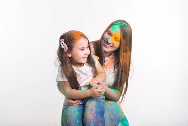 Familia, festival de holi y el concepto de vacaciones - Madre e hija pequeña cubiertas con polvo multicolor sonriendo sobre fondo blanco —  Fotos de Stock