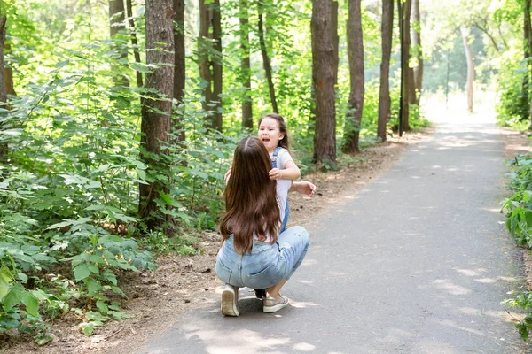 Familie, Natur, Menschen-Konzept - Mutter und Tochter umarmen sich im Park — Stockfoto