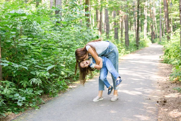 Familien-, Natur- und Kinderkonzept - Mutter und Tochter kuscheln und haben Spaß im Park — Stockfoto