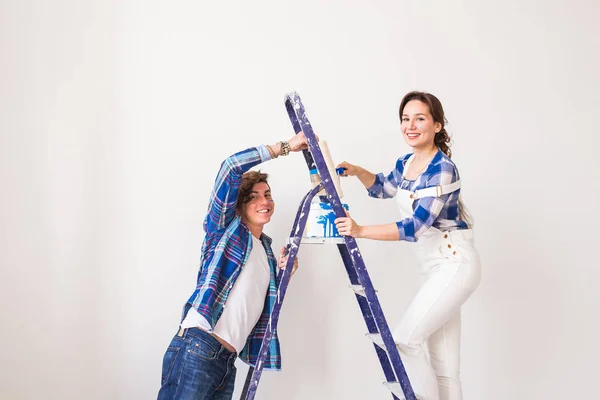 Família, renovação, felicidade e conceito de redecoração - jovem família fazendo reparos, pintando paredes juntas e rindo — Fotografia de Stock