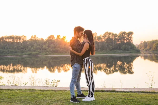Любовь, романтика, природа, люди - молодая прекрасная пара смотрит друг на друга и обнимается у озера — стоковое фото
