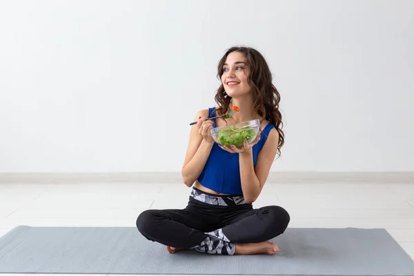 Estilo de vida saludable, personas y concepto deportivo - Mujer de yoga con un tazón de ensalada de verduras después de entrenar sobre fondo blanco —  Fotos de Stock