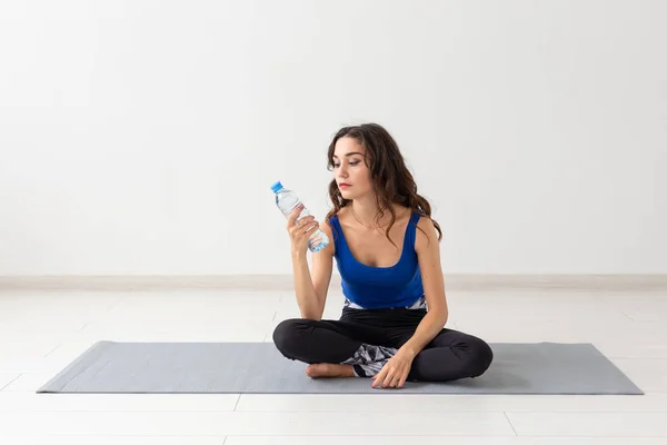 Estilo de vida saludable, personas y concepto deportivo - Joven hermosa mujer practicando yoga y agua potable — Foto de Stock