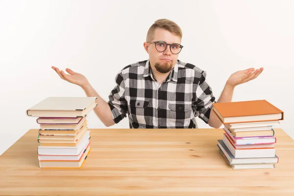 Esame, conoscenza ed educazione - studente confuso seduto a tavola con montagne di libri — Foto Stock