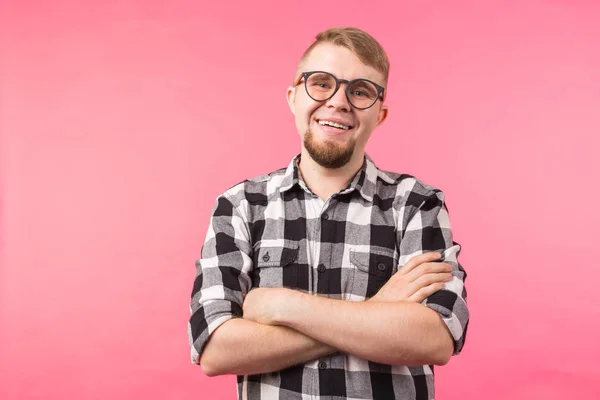 Retrato de hombre guapo de moda feliz en camisa a cuadros y gafas cruzando las manos sobre fondo rosa — Foto de Stock