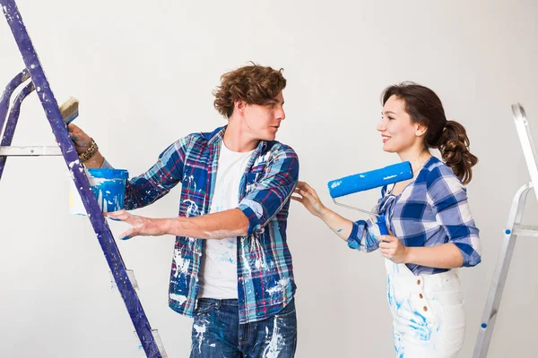 Repair, renovation and love couple concept - young family doing redecoration and painting walls together and laughing. — Stock Photo, Image