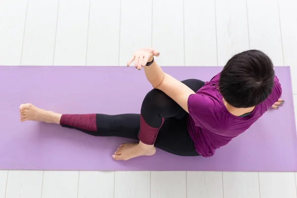Yoga, concepto de personas - una mujer de mediana edad haciendo un yoga y tratar de hacer una asana, vista superior —  Fotos de Stock